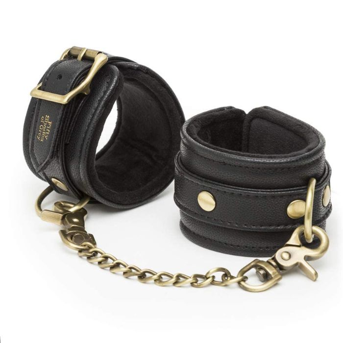 Fifty Shades of Grey Ankle Cuffs - Bound to You Black are a durable, handcrafted padded faux leather ankle cuffs with antique gold hardware. These cleverly designed cuffs have D-rings on each cuff for versatile bondage play and detachable chain with swivel lobster clasp at each end. This versatile set is compatible with the Bound to You spreader bar and hogtie.