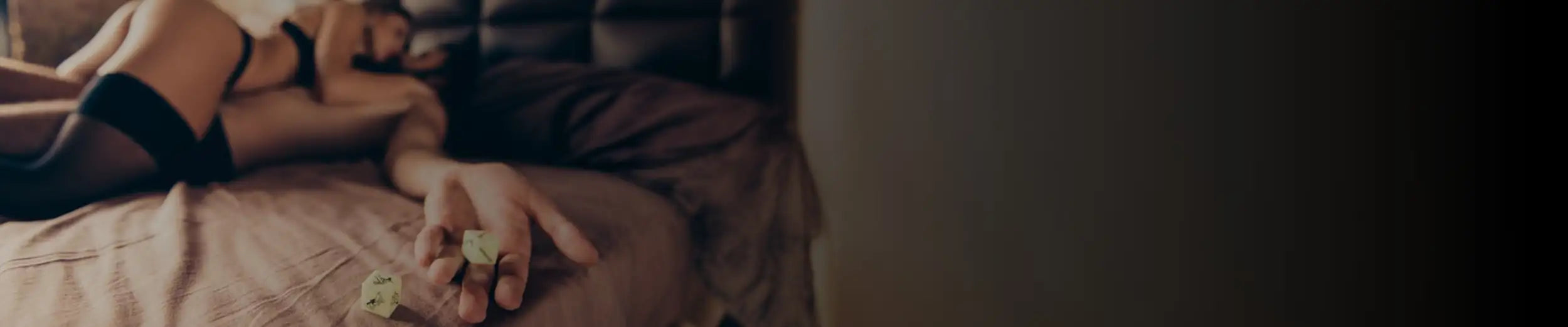 A pale yellow, translucent dice with black erotic symbols on its faces.