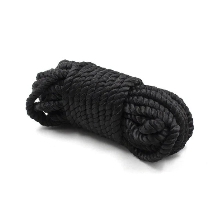 Black braided rope tightly coiled in a bundle from the everything bondage 12 piece kit with cuffs faux fur lined options