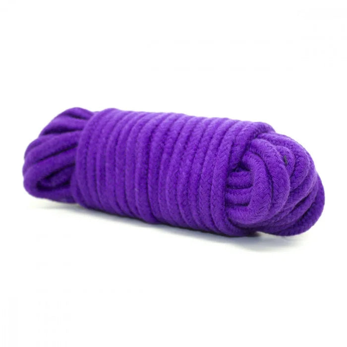 A tightly coiled vibrant purple rope with textured braided surface from everything bondage 12 piece kit with cuffs faux fur