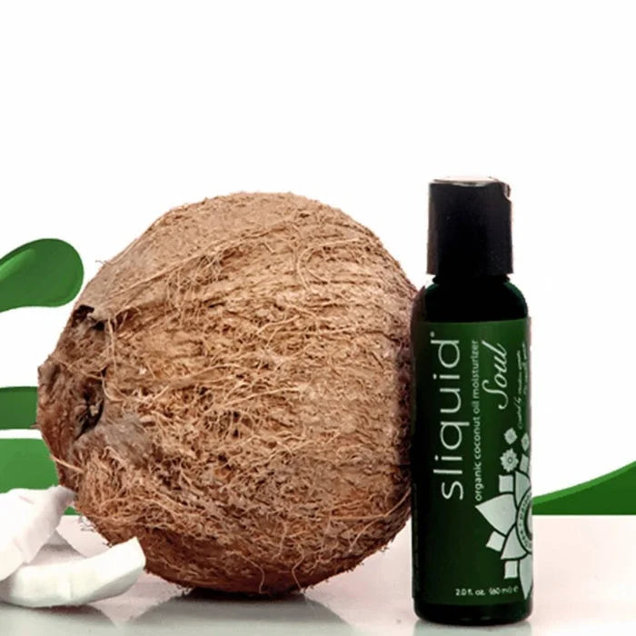 A dark green bottle of sliquid soul coconut massage oil with certified organic coconut oil and glycerin free formula next to a coconut