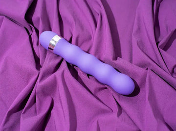 Purple silicone vibrato with a silver metallic band near the handle.