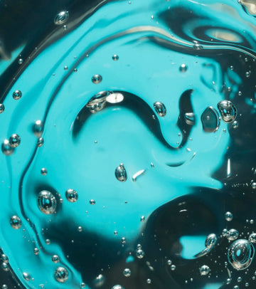 Vibrant turquoise liquid with swirling patterns and scattered clear bubbles.